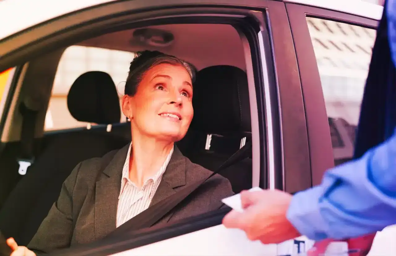Donna in auto riceve un foglio, forse una multa per assicurazione scaduta.