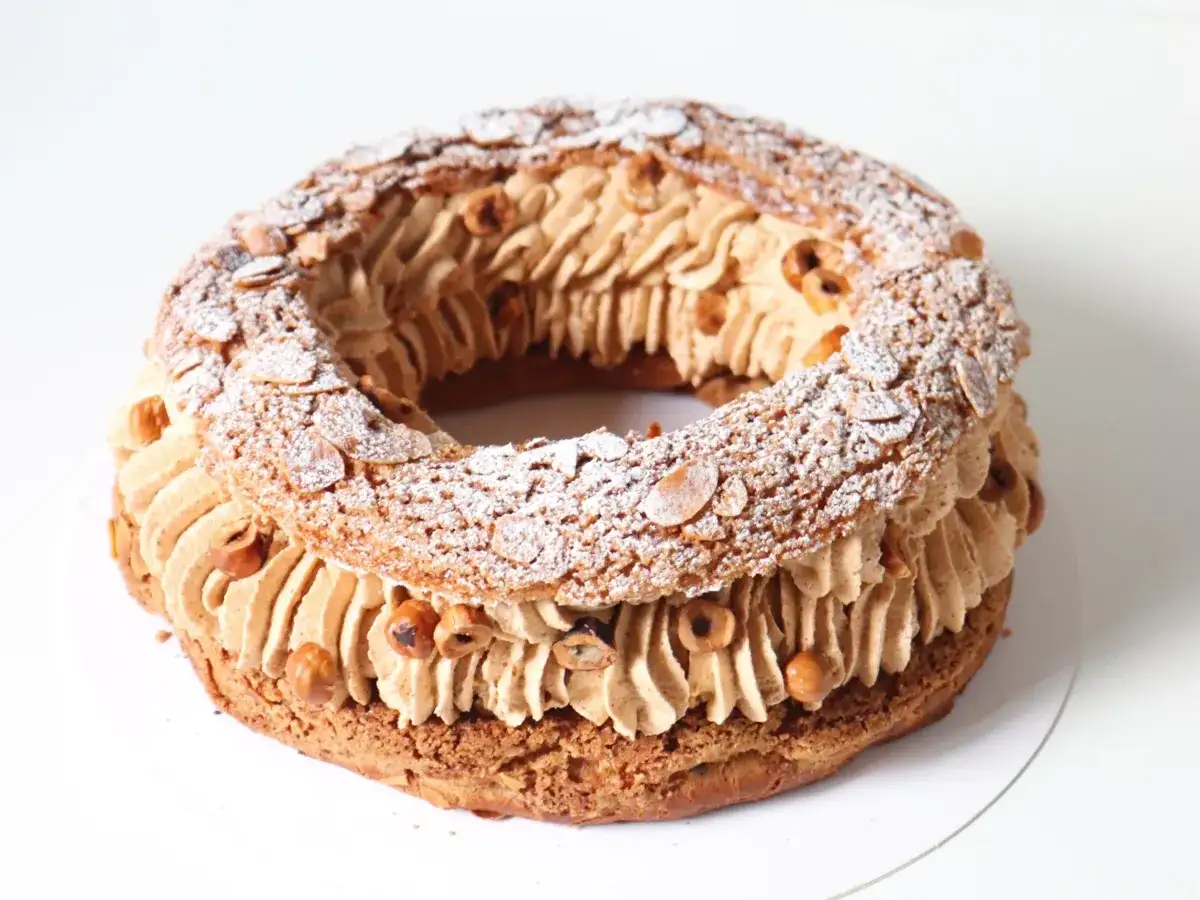 Un Paris-Brest rond, garni de cr&egrave;me pralin&eacute;e et parsem&eacute; d'amandes effil&eacute;es et de noisettes.
