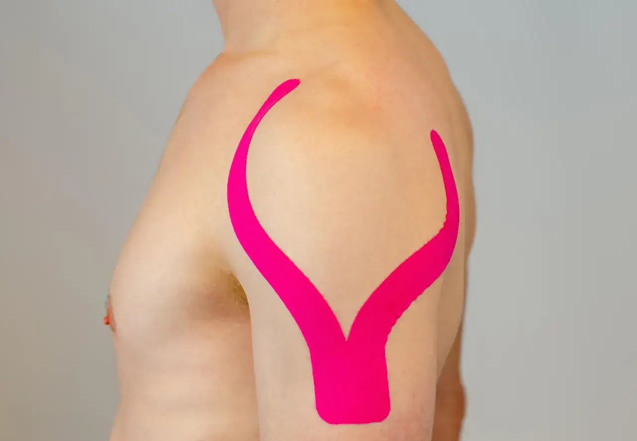 Schulter tapen f&uuml;r Unterst&uuml;tzung und Schmerzlinderung. Pinkes Kinesio-Tape st&uuml;tzt den Oberarm und die Schulter.
