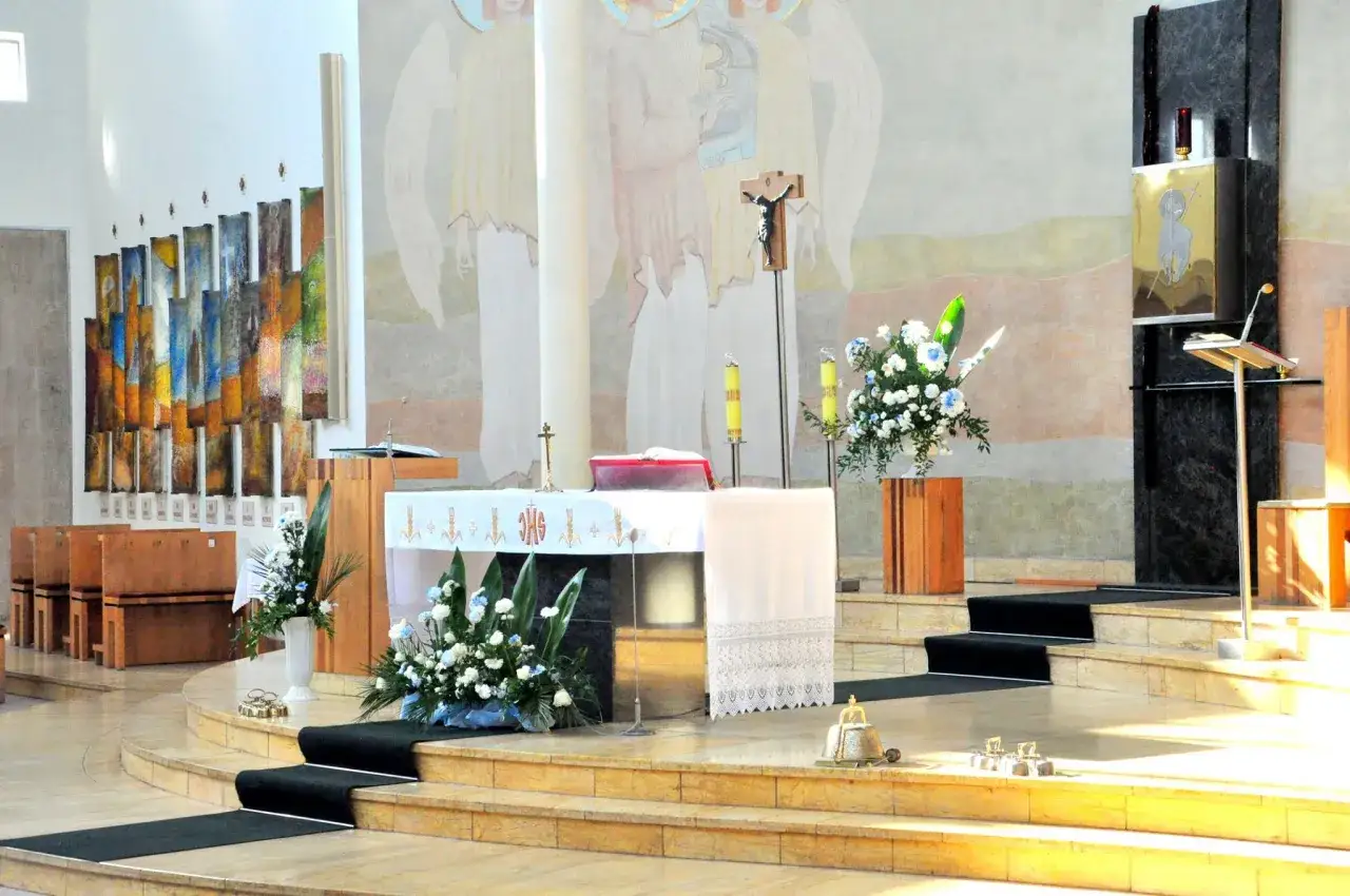Ołtarz w kościele, ozdobiony kwiatami i świecami. Czy opuszczając jedną mszę można iść do komunii? To pytanie zadaje sobie wielu wiernych.