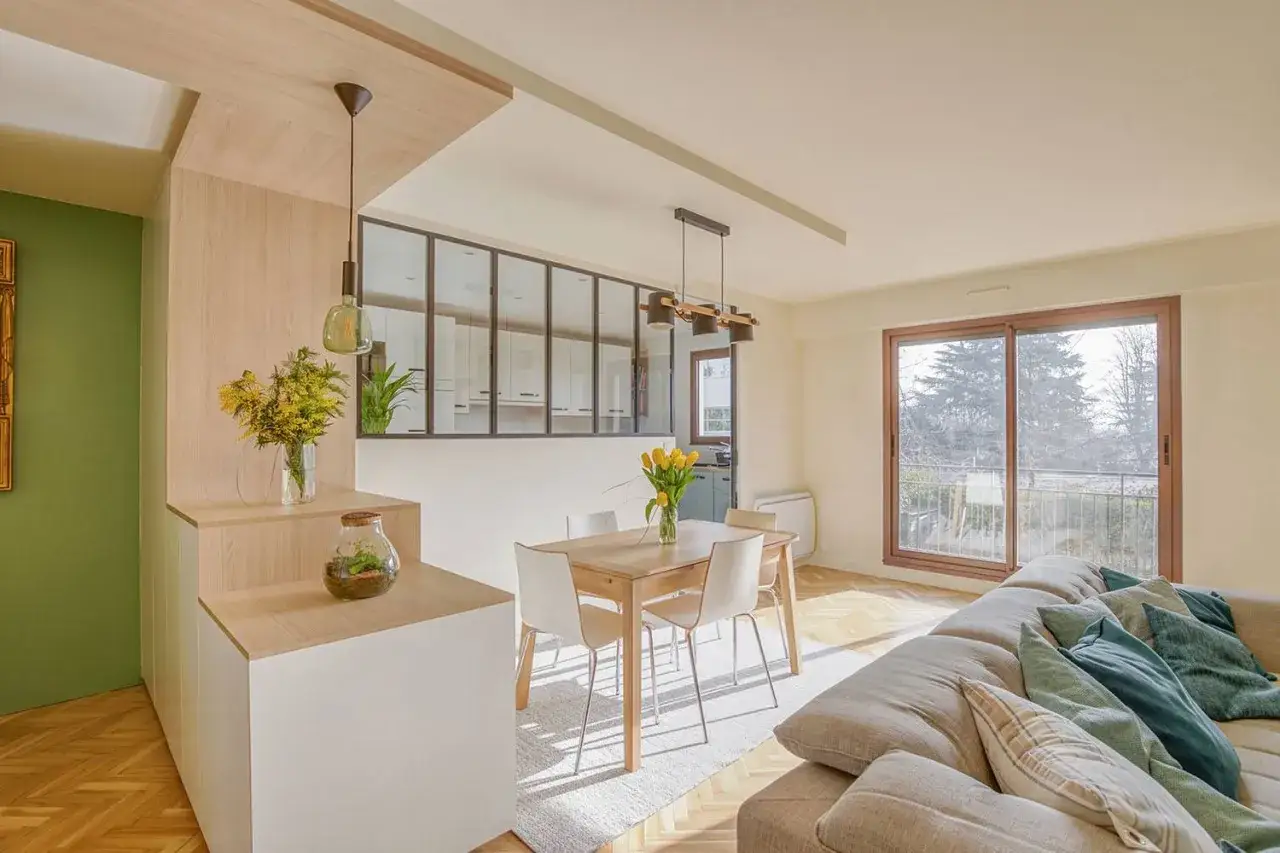 Aménagement appartement lumineux avec cuisine ouverte, salle à manger et salon. Bois clair, touches vertes et vue sur la nature.