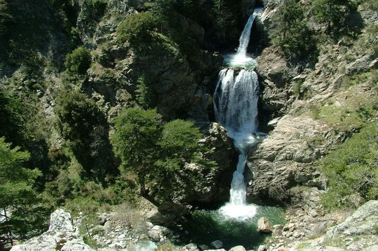 Cascate imponenti in Calabria, con acqua che scende su rocce e vegetazione rigogliosa, creando uno scenario naturale mozzafiato.