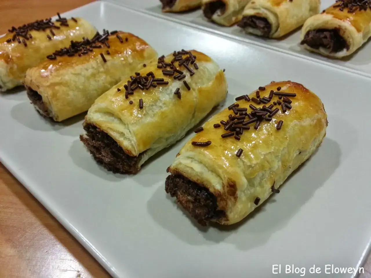 Napolitanas de chocolate caseras, enrolladas en hojaldre dorado y espolvoreadas con virutas de chocolate. ¡Perfectas para aprender como hacer napolitanas de chocolate!