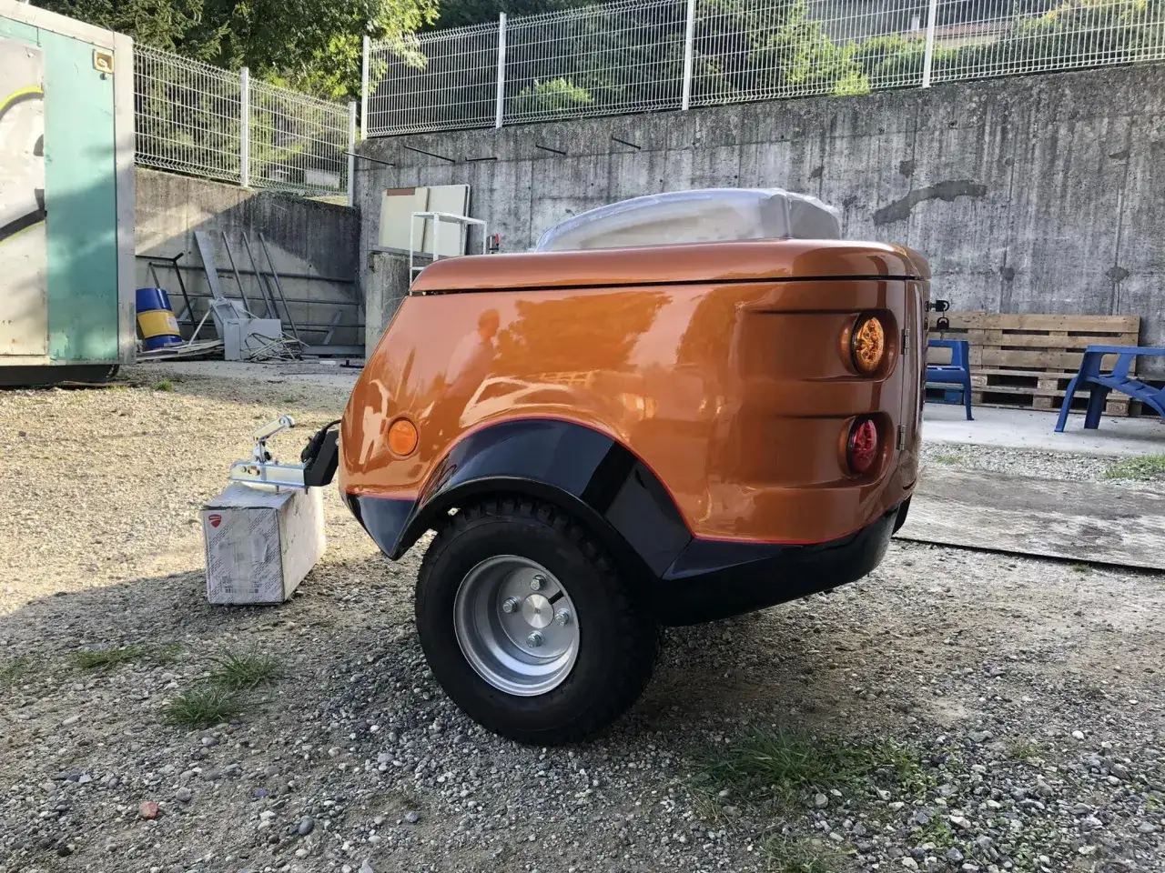Remorque pour chien moto, orange vif, avec un design aérodynamique et une roue unique. Parfait pour les aventures avec votre compagnon à quatre pattes.