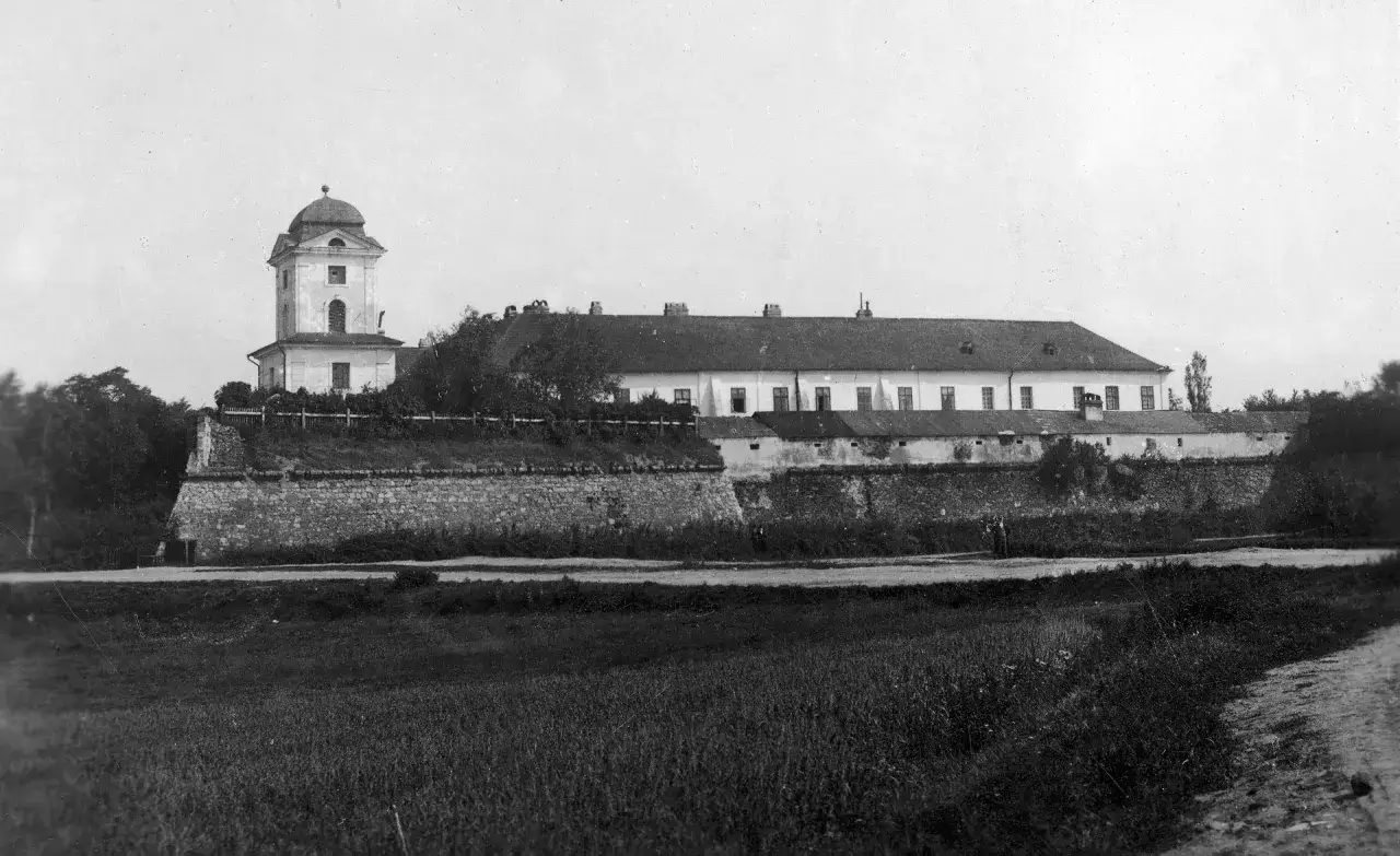 Zamek w Rzeszowie z wieżą i długim budynkiem, otoczony kamiennym murem.