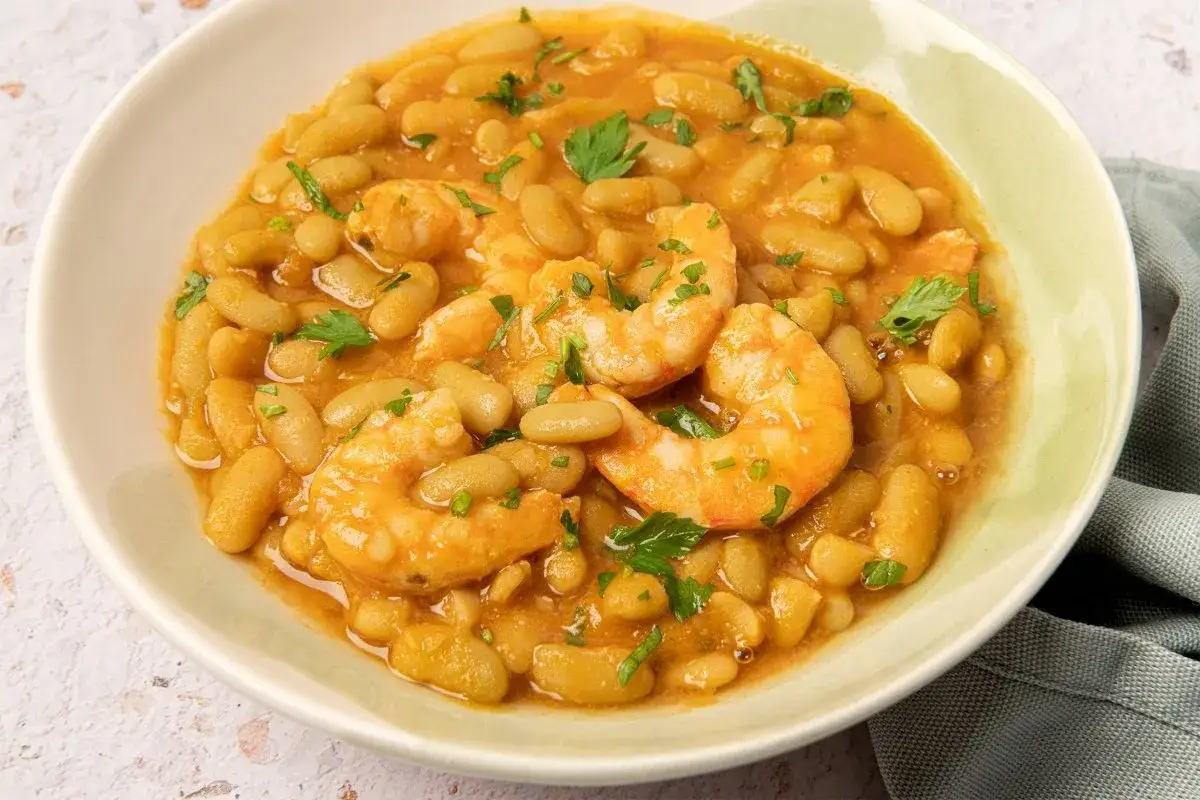 Plato de verdinas con langostinos, guisadas en una salsa sabrosa y adornadas con perejil fresco.