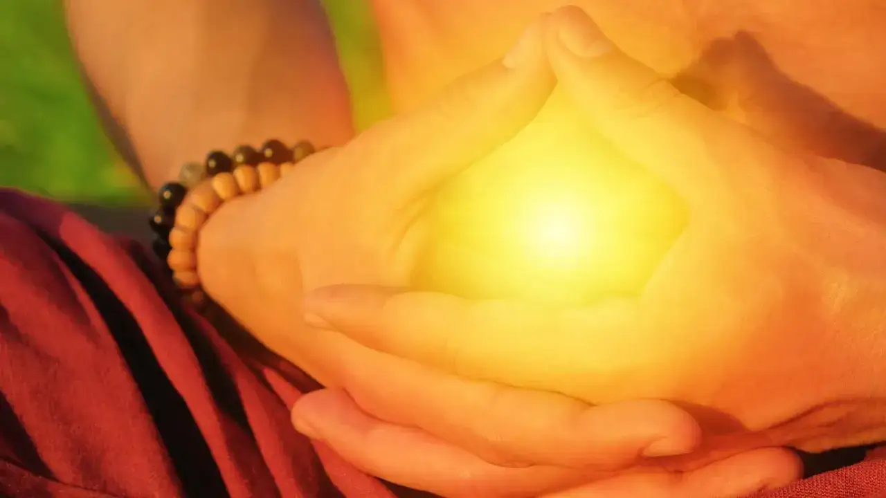 Mani giunte in meditazione, un bagliore giallo intenso tra le dita. Forse un modo per sciogliere i **terzo chakra bloccato sintomi**.