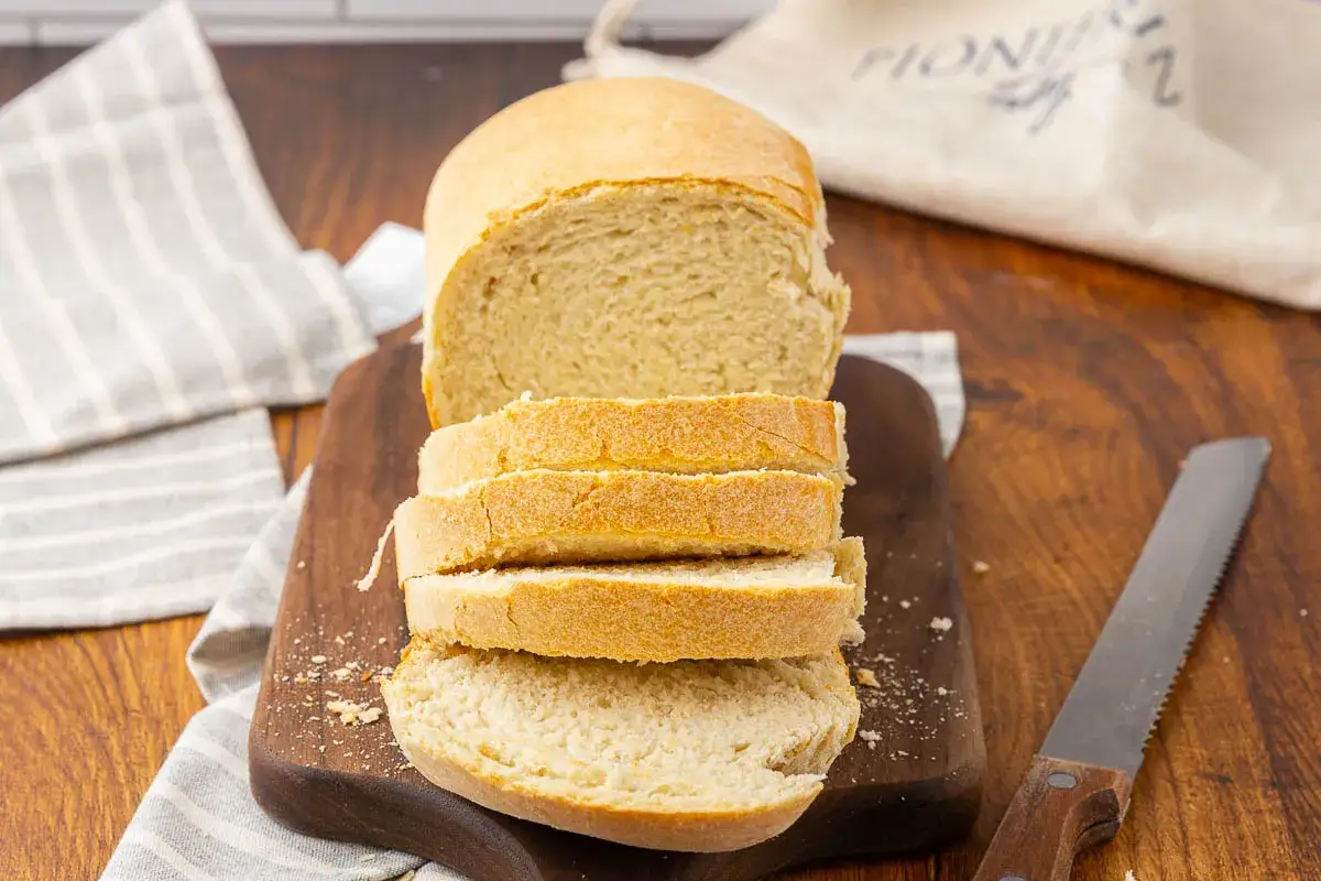 Pain de mie tranch&eacute; sur une planche en bois, avec un couteau. Id&eacute;al pour savoir par quoi remplacer la levure boulang&egrave;re.