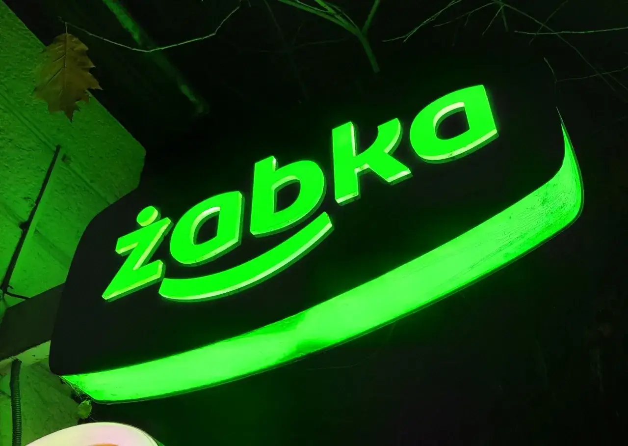 Jasny neonowy szyld Żabki, który może skłonić do zastanowienia, ile zarabia kasjer w Żabce netto.