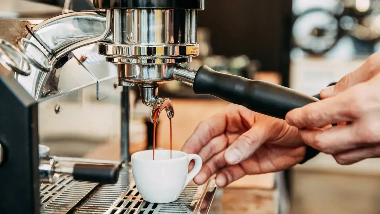 Frisch gebr&uuml;hter Espresso flie&szlig;t in eine Tasse. Die wichtigsten Kaffee Zutaten sind Wasser und ger&ouml;stete Bohnen.