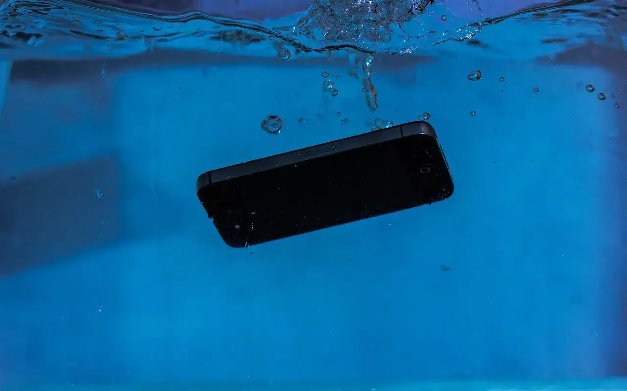 Czarny iPhone 13 zanurza się w wodzie, a bąbelki unoszą się wokół. Czy iPhone 13 jest wodoszczelny?