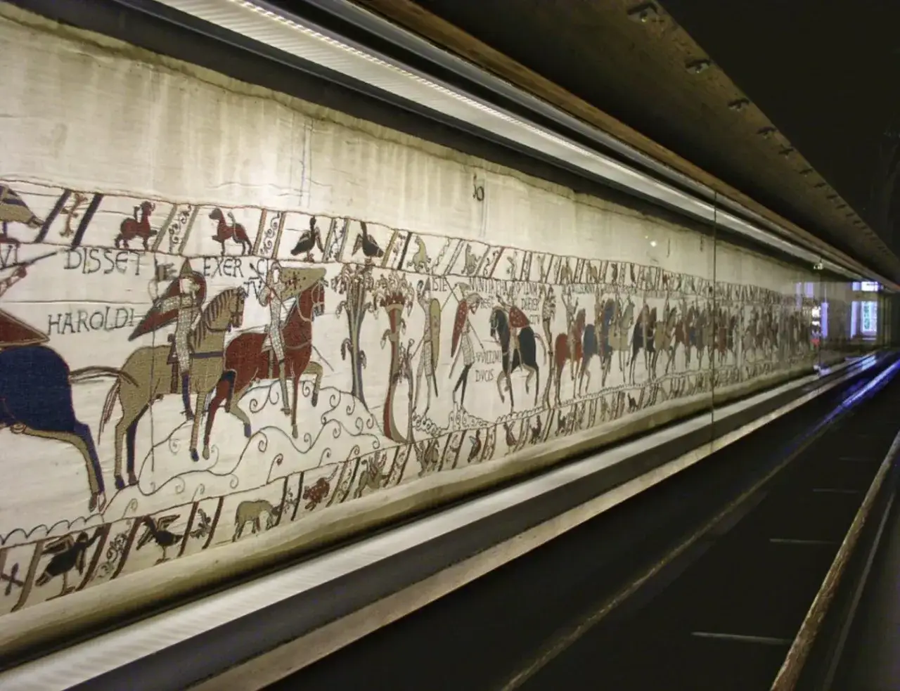 Bayeuxtapeten museum visar en l&aring;ng broderad duk med scener av strid och kungligheter.