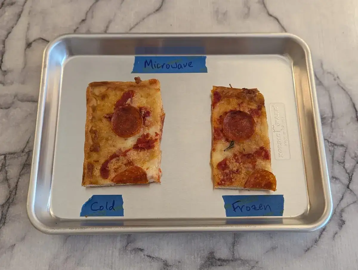 Dwa kawałki pizzy na tacy: jeden z etykietą 