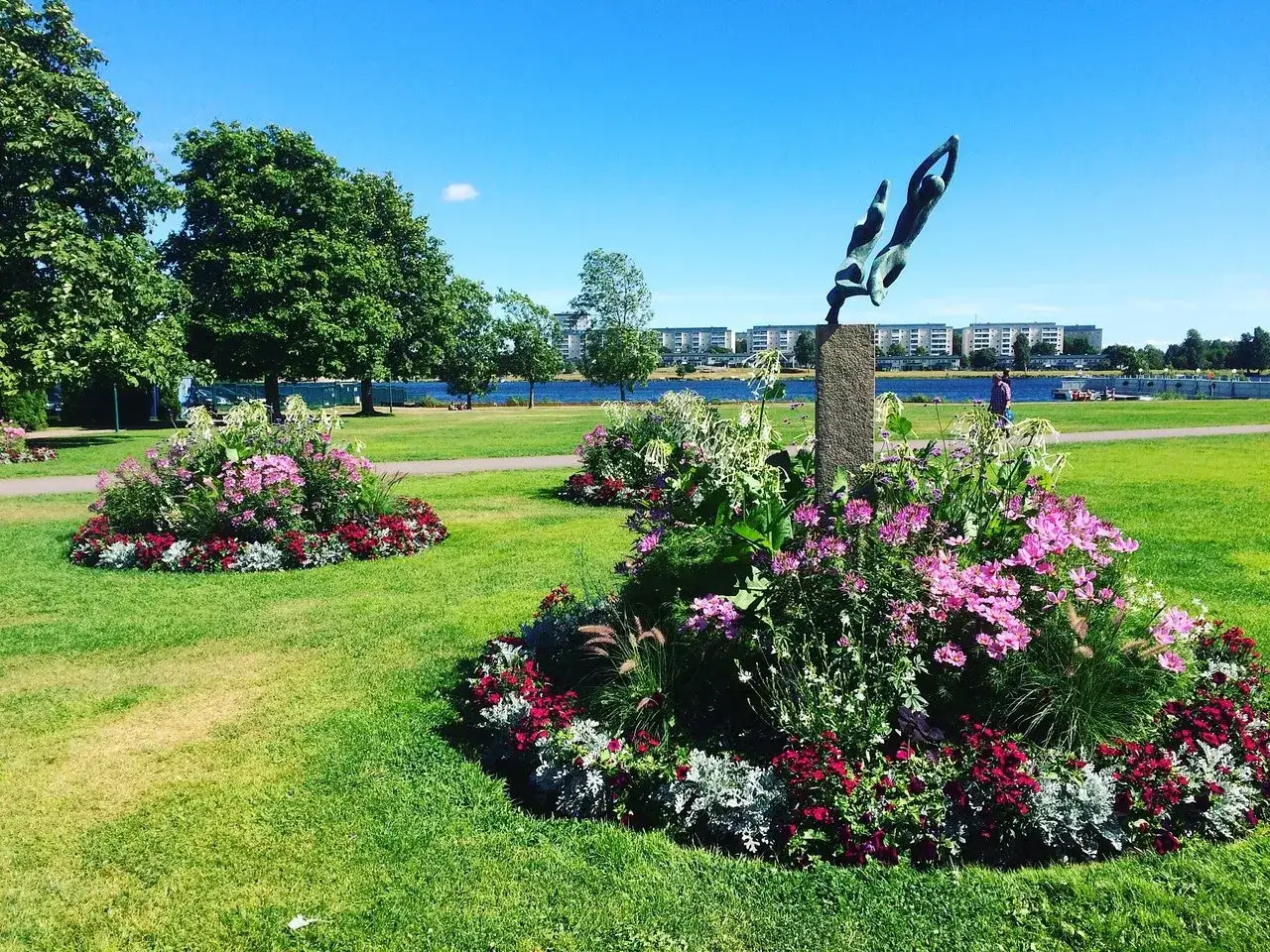 Vacker park med blomsterarrangemang och en dykande staty. Perfekt f&ouml;r aktiviteter i Karlstad en solig dag.