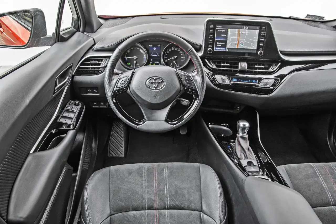 Wnętrze Toyoty C-HR z ekranem nawigacji i kierownicą. Sprawdź aktualną toyota chr cena i wyposażenie.