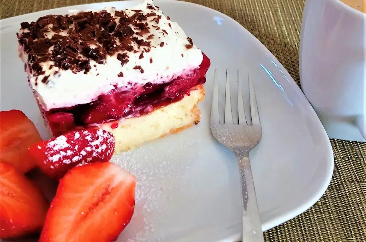 Proste ciasto z serkiem mascarpone i galaretką, udekorowane bitą śmietaną i czekoladą, podane z truskawkami.