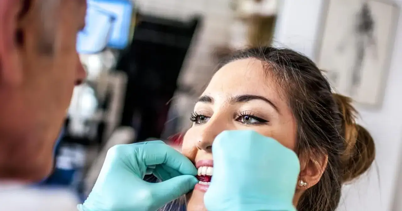 Dentysta zakłada pacjentce nakładkę na zęby, by pomóc w walce z bruksizmem. Domowe sposoby na bruksizm mogą być wsparciem.