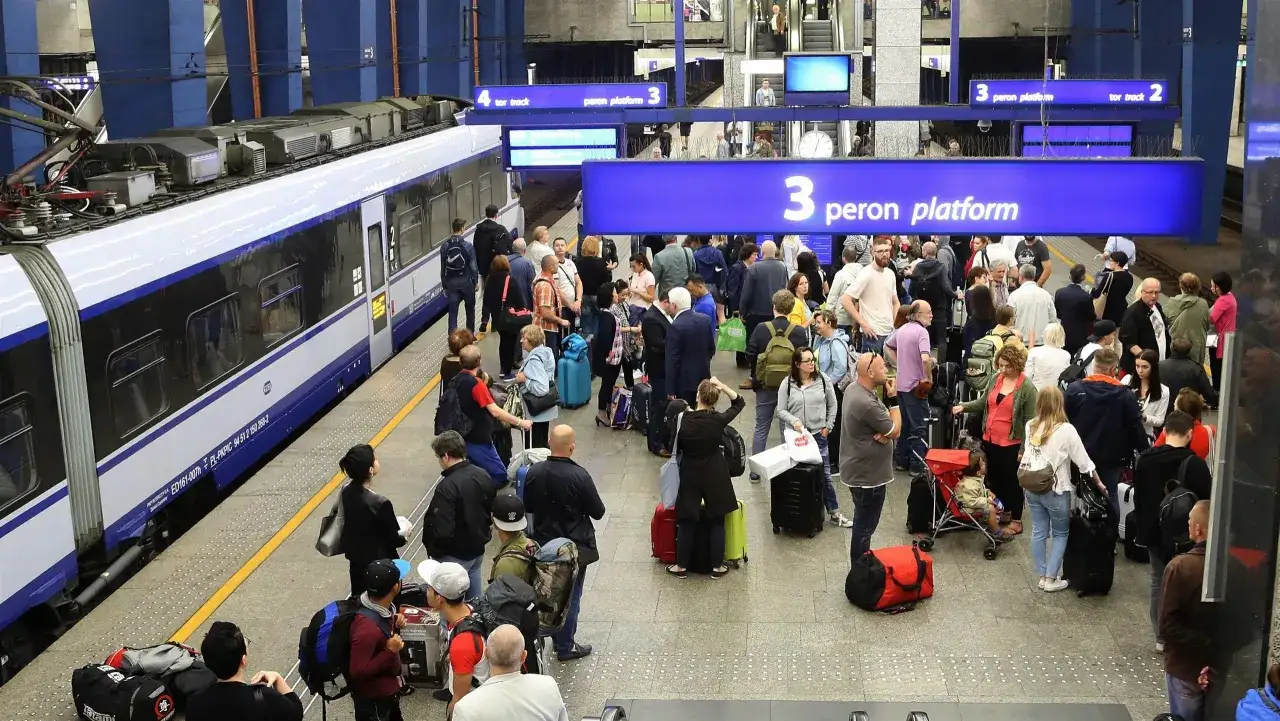 Tłum ludzi czeka na pociąg Intercity. Tablica informuje, z którego peronu odjeżdża pociąg: peron 3.