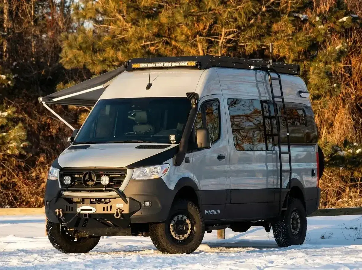Camping car tout terrain pr&ecirc;t pour l'aventure, avec auvent, &eacute;chelle, snorkel et lumi&egrave;res LED sur le toit.