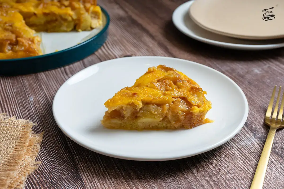 Rebanada de pudin de manzana casero, con trozos de manzana caramelizada y una base dorada.
