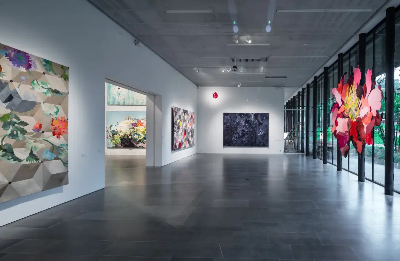 Konsthall med blomstermotiv och geometriska mönster. En stor röd blomma hänger i taket, kanske en del av Sven Harrys samling.