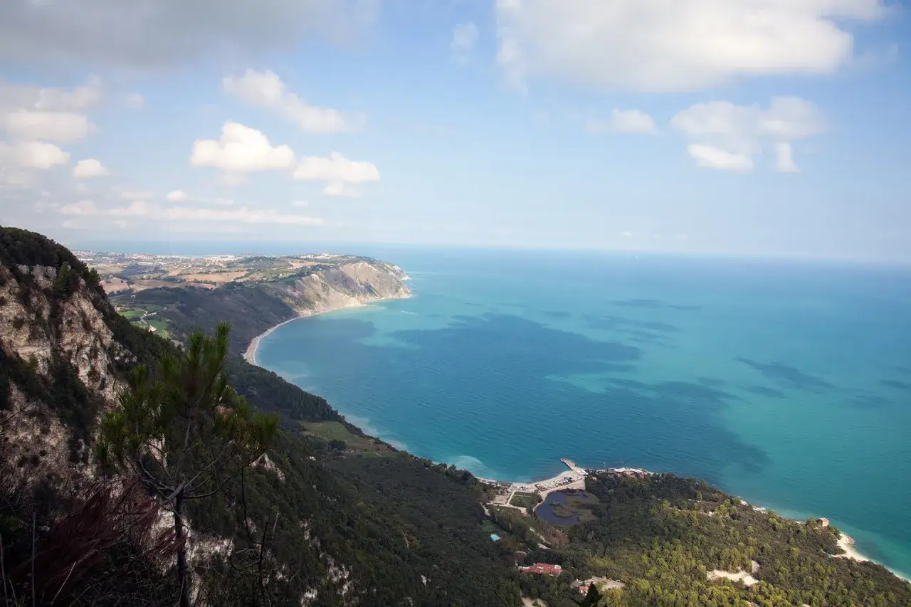 Vista mozzafiato dal belvedere Monte Conero: mare azzurro, costa frastagliata e vegetazione lussureggiante.