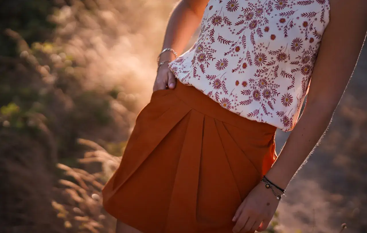 Jupe tulipe orange avec plis, portée avec un haut fleuri. Un patron de couture pour un style estival.