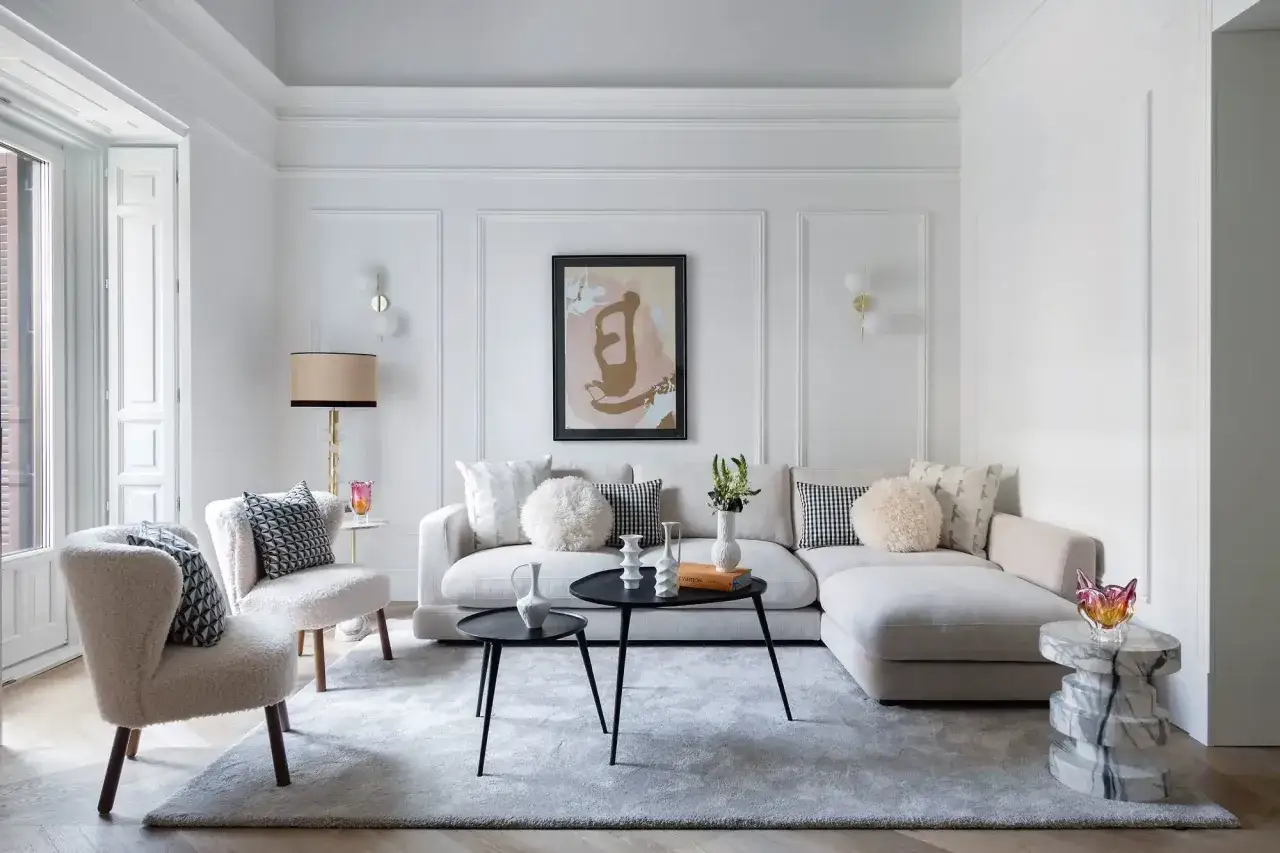 Elegante salón con sofás blancos, sillones de borrego y **salones con molduras en paredes** que realzan la decoración.