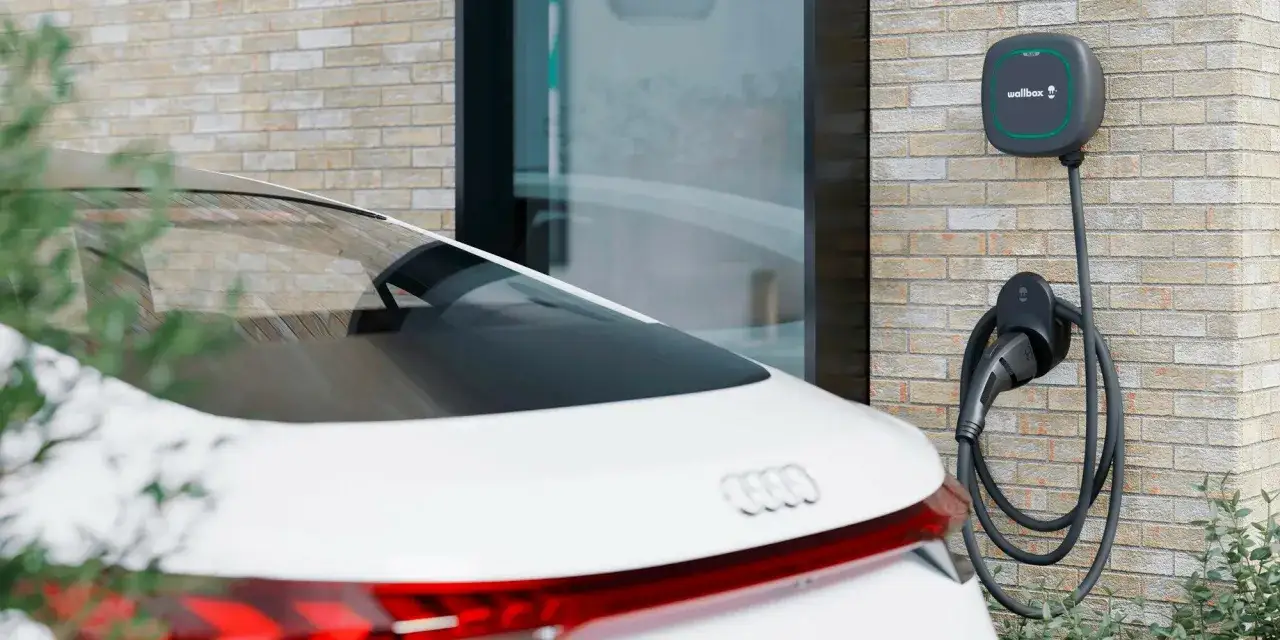 Cargador de coche el&eacute;ctrico en pared de ladrillo, listo para responder cuanto tarda en cargar un coche el&eacute;ctrico en casa.