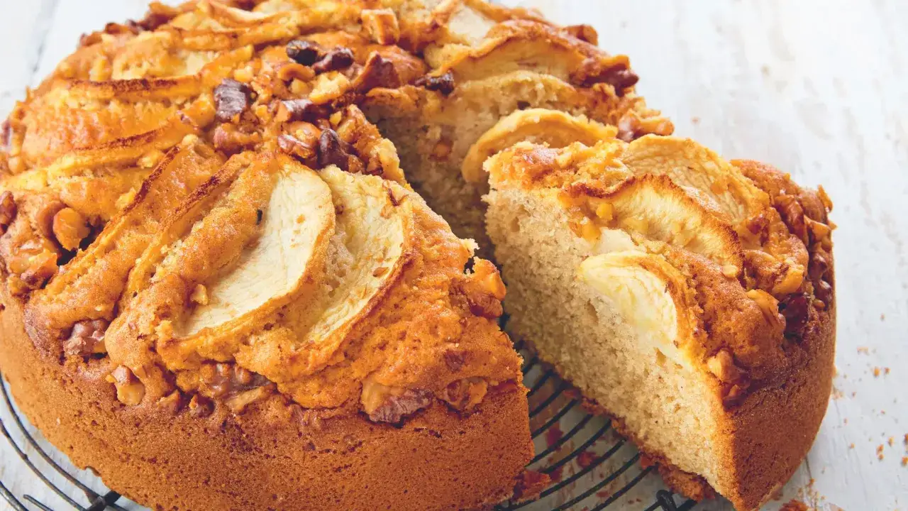 Un délicieux gâteau aux pommes et noix de grand-mère, avec des tranches de pommes et des noix croquantes sur le dessus.
