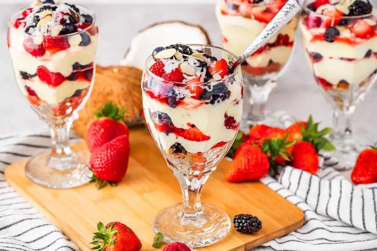 Desserts en verrine avec fruits rouges, cr&egrave;me onctueuse et copeaux de noix de coco. Un d&eacute;lice qui rappelle le **curd mangue passion**.