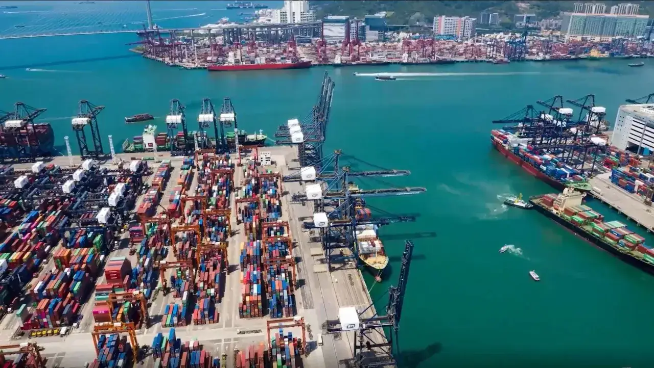 Ein geschäftiger **Hong Kong Port** mit Kränen, Frachtschiffen und Containern, die auf Verladung warten.