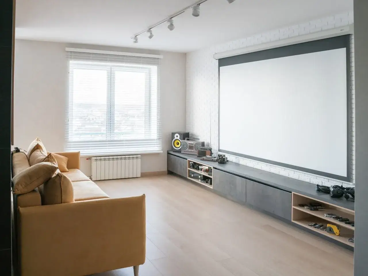Nowoczesny salon z kanapą i wielkim ekranem. **Projektor zamiast TV** oferuje kinowe wrażenia w domu.