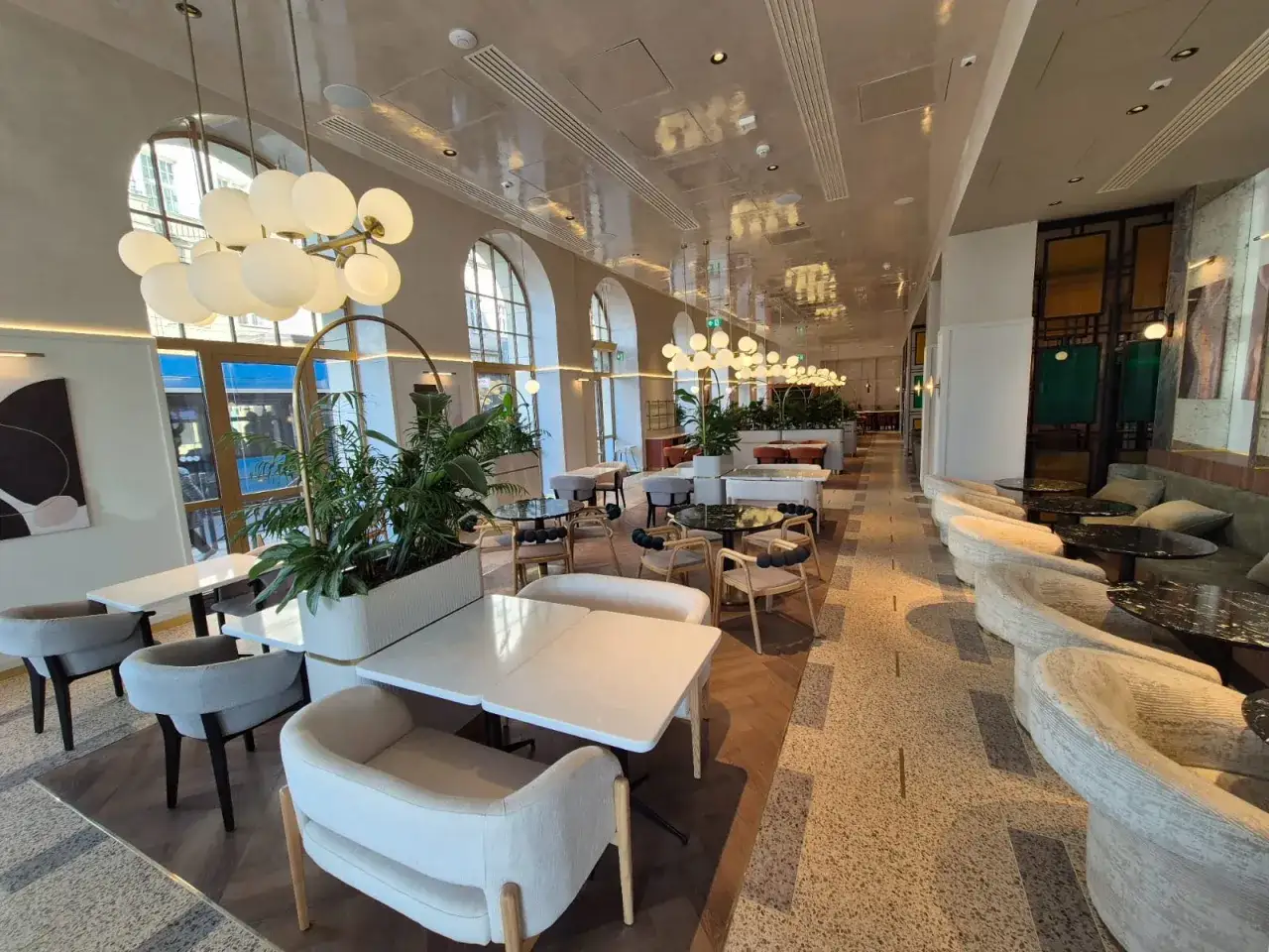 Eleganckie wnętrze restauracji w Grand Hotel Wrocław. Jasne stoły, wygodne fotele i bujna roślinność tworzą przytulną atmosferę.