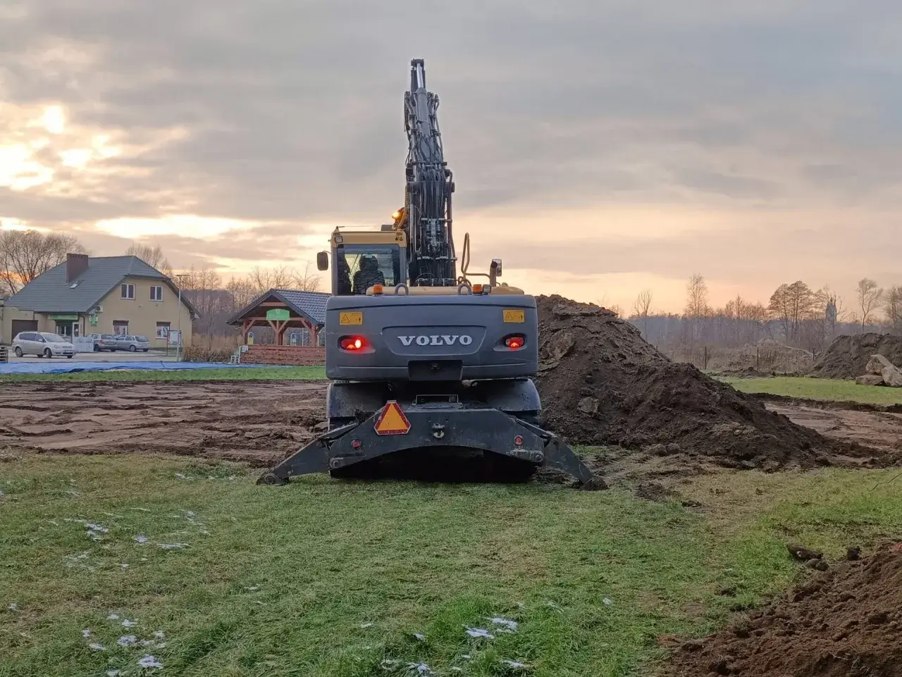 Koparka Volvo na placu budowy. Widok z tyłu na maszynę i hałdy ziemi. Sprawdzamy prace ziemne cennik.