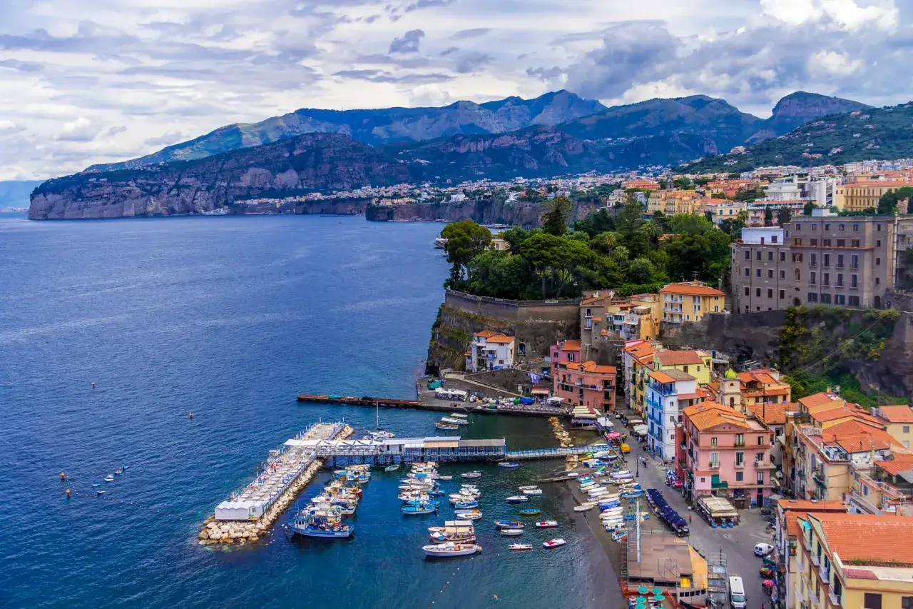 Widok na zatokę i miasteczko Sorrento z kolorowymi domami, portem pełnym łodzi i g&oacute;rami w tle. Idealne miejsce na odkrywanie atrakcji.