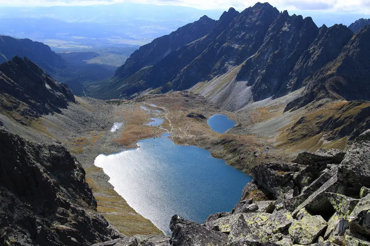 Widok na Tatry z drugiego najwyższego szczytu w Polsce. Błękitne jeziora otoczone skalistymi zboczami i jesienną roślinnością.