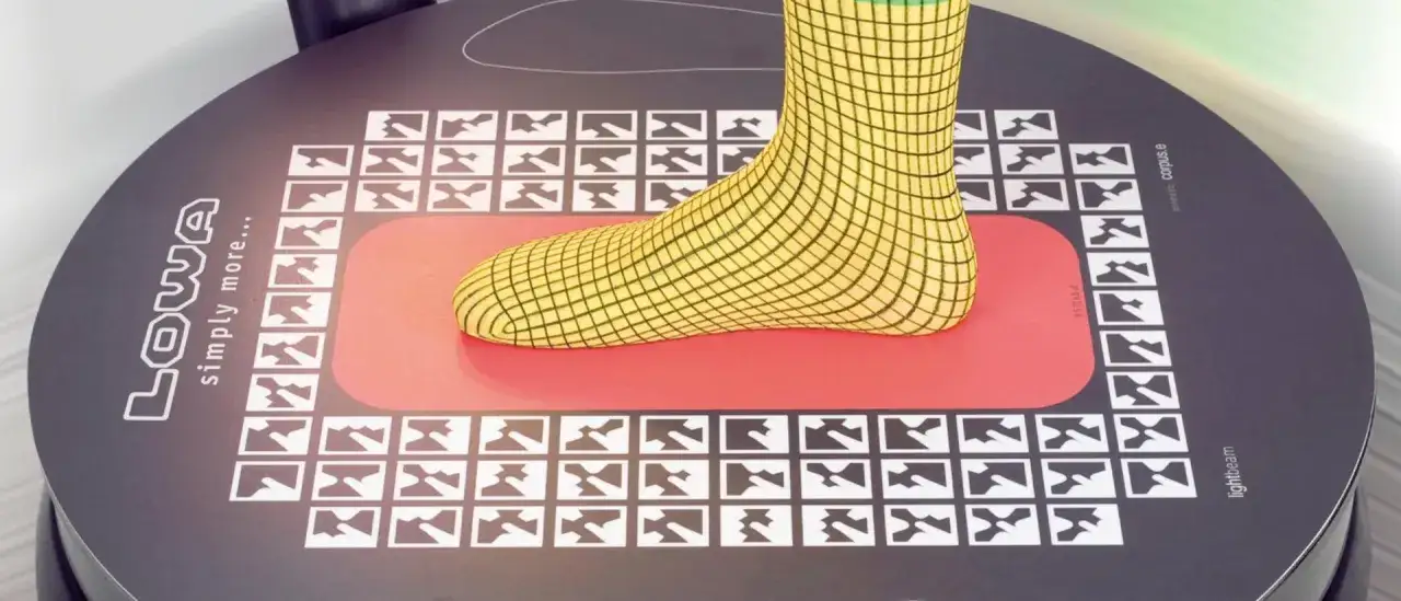 A foot in a yellow grid sock rests on a red mat on a circular device. This device helps determine what size walking boot do I need.