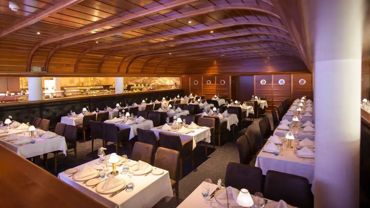 Elegantes Restaurant mit vielen gedeckten Tischen, Holzw&auml;nden und Bullaugen. Hier k&ouml;nnte die Bell Rock Restaurant Speisekarte f&uuml;r ein festliches Mahl liegen.