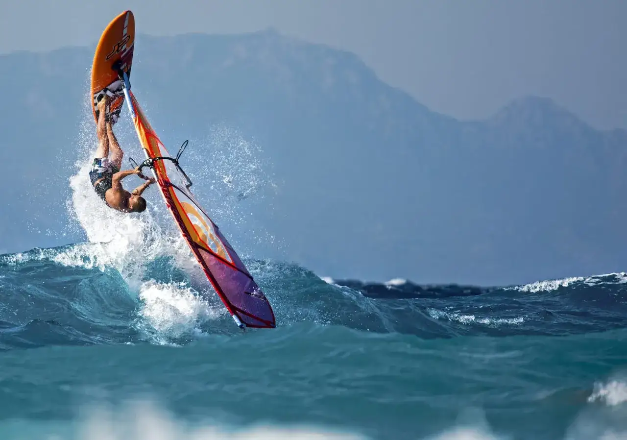 Windsurfer wykonuje ewolucję na falach w Ixia Rodos. W tle góry.