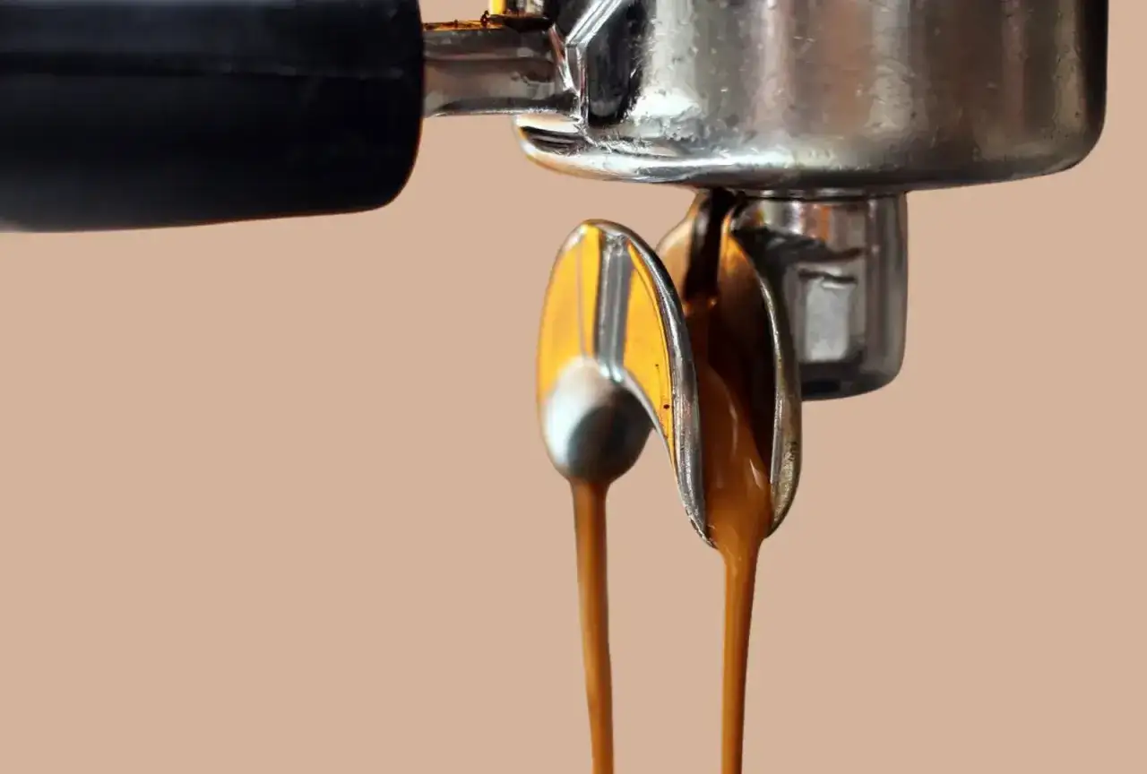 Frisch gebrühter Kaffee mit schöner Crema fließt aus einer normalen Kaffeemaschine.