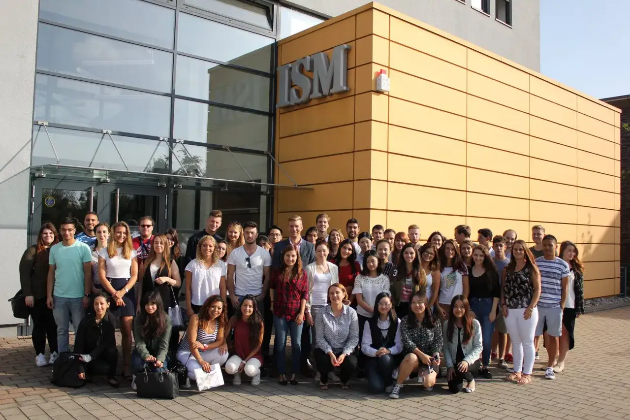 Eine Gruppe junger Leute vor dem ISM-Geb&auml;ude in Hamburg. Sie sind zuk&uuml;nftige Marketing-Master-Studenten, bereit, die Welt des Marketings zu erobern.