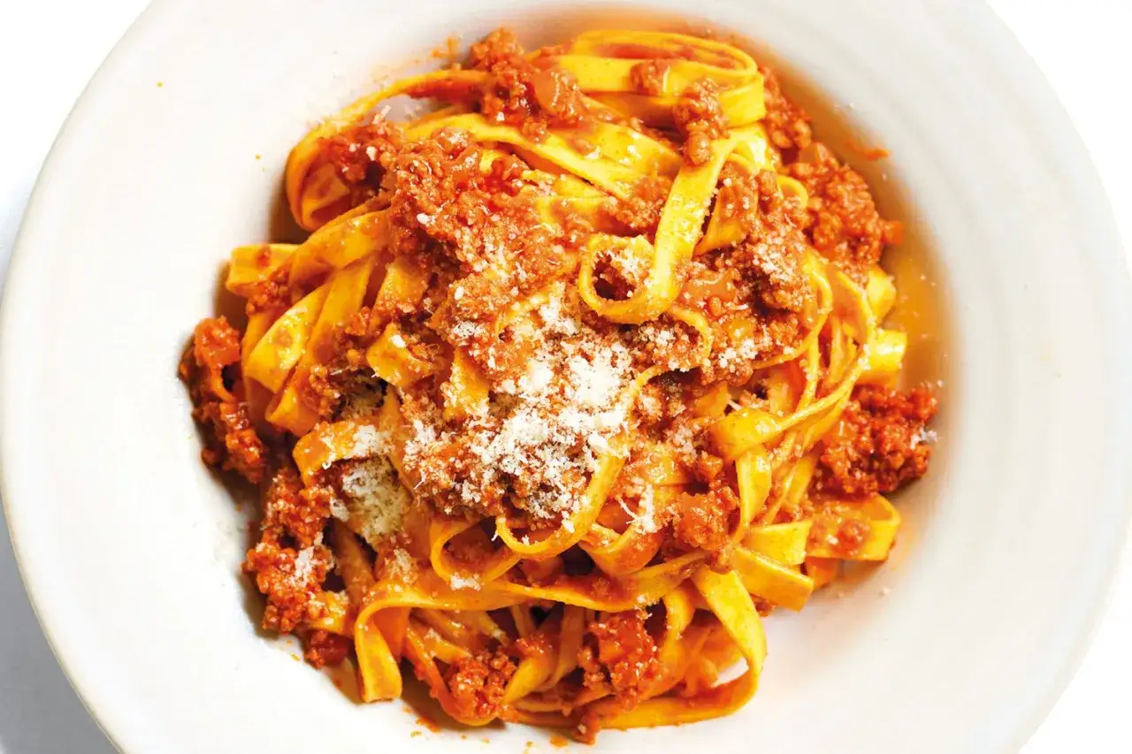 Un piatto invitante di tagliatelle al rag&ugrave;, condite con abbondante sugo di carne e una spolverata di parmigiano.