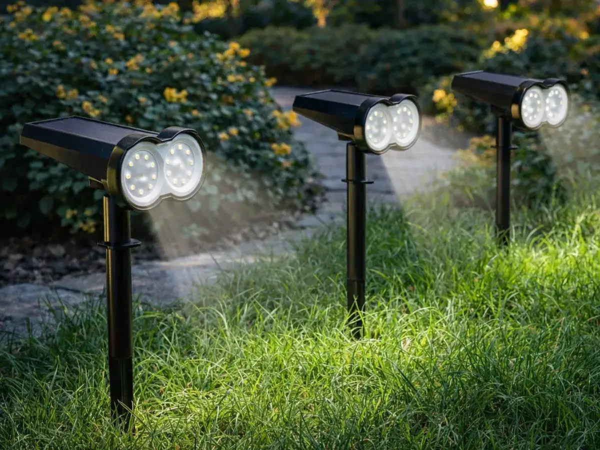 Trzy lampki solarne LED oświetlają trawnik i krzewy, tworząc magiczną atmosferę w ogrodzie.
