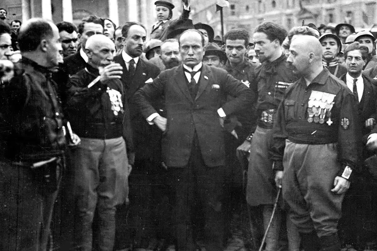 Mussolini omgiven av män i uniform. Bilden ger en känsla av makt och auktoritet, och visar vad fascism betyder för många.