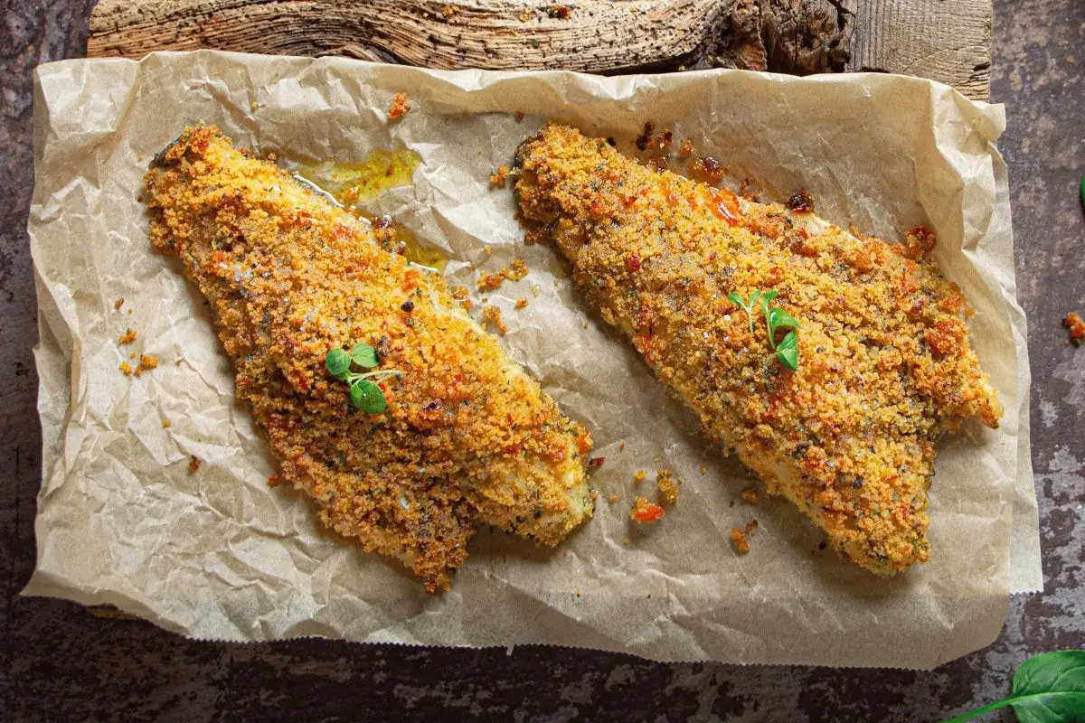 Filetti di orata in padella gratinati, dorati e croccanti, guarniti con erbe fresche. Un piatto saporito e invitante.
