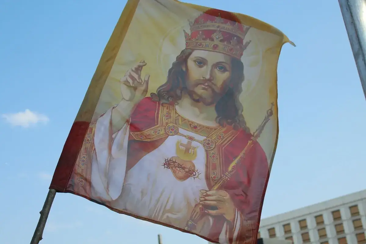 Flaga z wizerunkiem Jezusa Chrystusa Króla Wszechświata, unosząca się na tle błękitnego nieba.