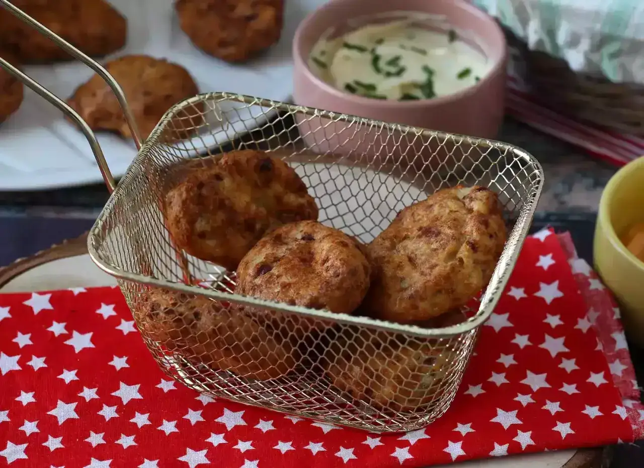 Krispiga chicken nuggets i airfryer, serverade i en guldf&auml;rgad korg. En sk&aring;l med kr&auml;mig dipp syns i bakgrunden.