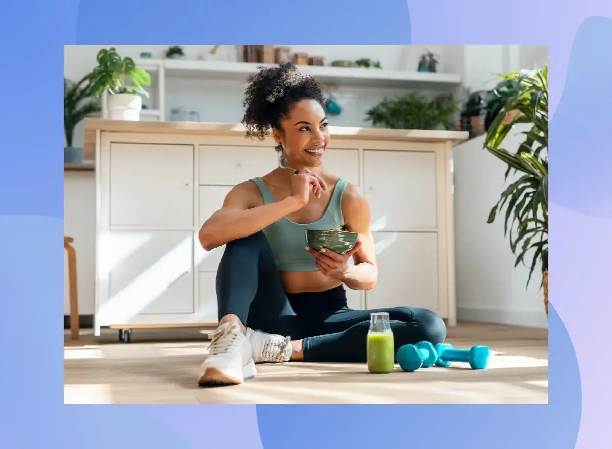 Donna con fisico endomorfo, sorride mentre mangia una ciotola di cereali, con un frullato verde e pesi accanto.