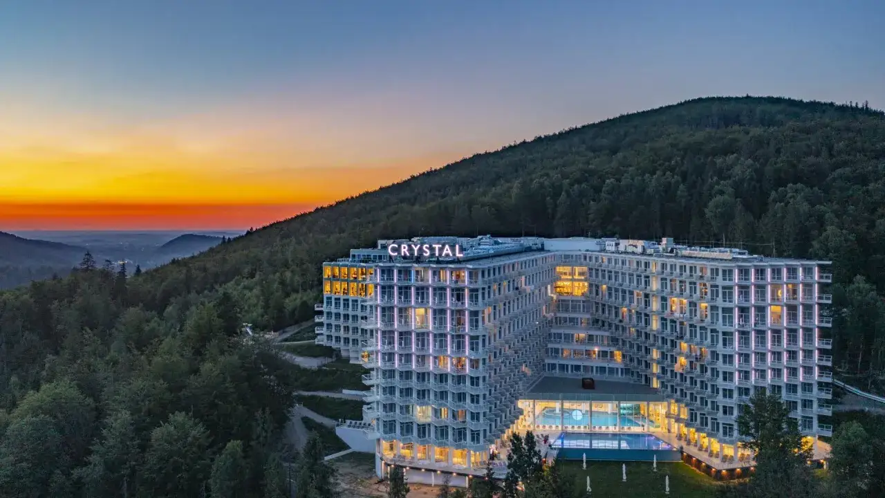Nowoczesny Crystal Mountain Hotel Wisła w otoczeniu lasu, o zachodzie słońca.